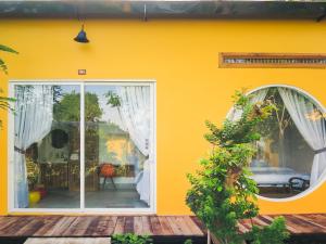 a yellow house with white curtains and a patio at Binh Minh Eco Lodge in Can Tho