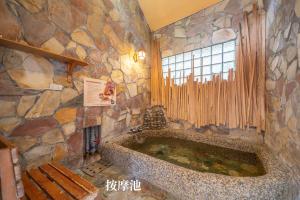 礁渓郷にある一口井溫泉 One Well Hot Springの窓付きの客室で、大きな石造りのバスタブが備わります。