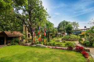 a garden with flags and flowers in front of a building at Chitwan Tiger Camp in Sauraha