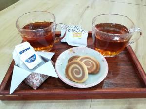 a tray with two glasses of tea and a plate of biscuits at Sakura Guest House in Dharamshala