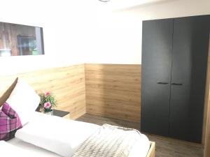 ein Schlafzimmer mit einem weißen Bett und einem schwarzen Schrank in der Unterkunft APART six-o-nine in Schwendau