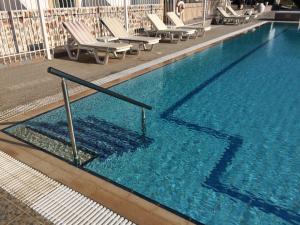 a large blue swimming pool with chaises and chairs at Paraschos Studios Kos in Kardamaina