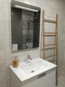 ein Badezimmer mit einem weißen Waschbecken und einem Spiegel in der Unterkunft TRIANA PUREZA 12-14 in Sevilla
