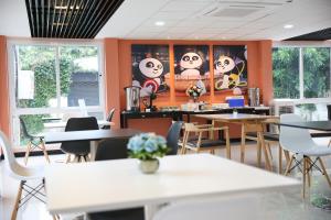 a dining room with tables and chairs and orange walls at Lucky panda Hotel in Chiang Mai