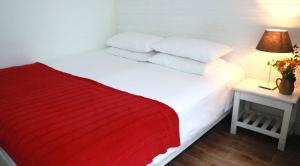 a white bed with a red blanket and two pillows at Peking Station Hostel in Beijing