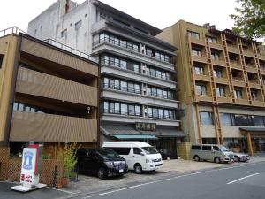 een groot gebouw met auto's geparkeerd voor het bij Yamagisi Ryokan in Fujikawaguchiko