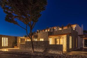 a building with a tree in front of it at night at Omnia Mykonos Boutique Hotel & Suites in Ornos