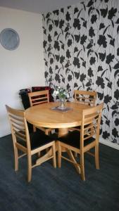 una mesa de madera con 2 sillas y un jarrón con flores en Lerwick Garden Apartment en Inverness