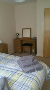 a bedroom with a bed and a dresser and a mirror at Lerwick Garden Cottage in Inverness