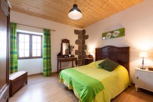 1 dormitorio con 1 cama con colcha verde en Villa Canaria piscina jacuzzi jardín, en Santa María de Guía de Gran Canaria