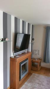ein Wohnzimmer mit einem TV auf dem Kamin in der Unterkunft The Cobblers in Inverness