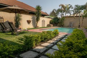 a swimming pool with two chairs and an umbrella at Fallsway Villas in Lusaka