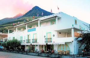 a large white building with a mountain in the background at Hotel Ossidiana Stromboli Center in Stromboli