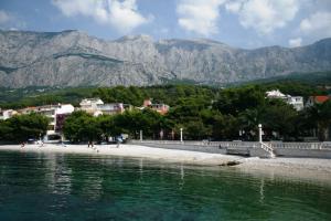 a beach with mountains in the background and people on the beach at Hotel Villa Marija in Tučepi