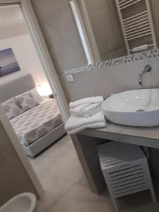 ein Bad mit einem Waschbecken und einem Spiegel in der Unterkunft Accanto a te - Charme Rooms in Vieste