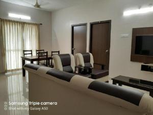 uma sala de espera com cadeiras e uma televisão num quarto em Viswa Residency by Azalea em Madurai