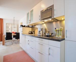 a kitchen with white cabinets and a counter top at Jann-Berghaus-Straße 29 in Norderney +4 photos