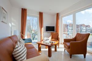 a living room with a couch and chairs and a tv at Jann-Berghaus-Straße 29 in Norderney