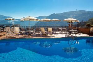 basen ze stołami, krzesłami i parasolami w obiekcie Hotel La Vue d'Or w Sorrento