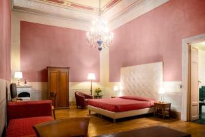 a bedroom with a red bed and a chandelier at Hotel Bretagna Heritage - Alfieri Collezione in Florence