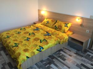 a bedroom with a bed with a yellow comforter and pillows at apartament parc cetate in Alba Iulia