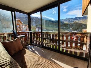 Pokój z kanapą i dużym oknem z widokiem na góry w obiekcie Le Serac W6 appartement avec véranda en angle vue panoramique gérer par particulier sur place w Val Thorens