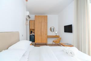 a bedroom with two white beds and a kitchen at Omnia Mykonos Boutique Hotel & Suites in Ornos