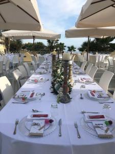 einem langen Tisch mit Tellern und Besteck in der Unterkunft Grand Hotel La Playa in Sperlonga