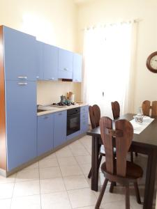 a kitchen with blue cabinets and a table and chairs at Casa Mia Apartment in Riposto