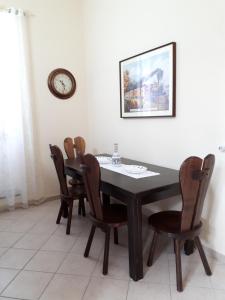 a dining room table with chairs and a clock on the wall at Casa Mia Apartment in Riposto