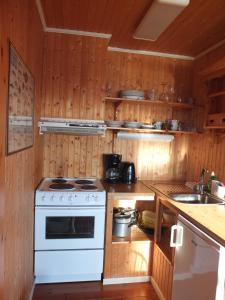 eine Küche mit einem weißen Herd und Holzwänden in der Unterkunft Tyskhella Rorbuer in Kabelvåg