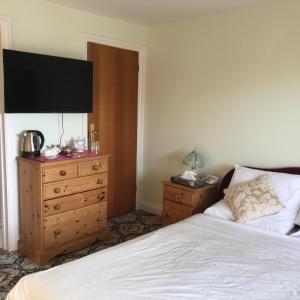 a bedroom with a bed and a dresser and a television at Orchard Manor in Probus