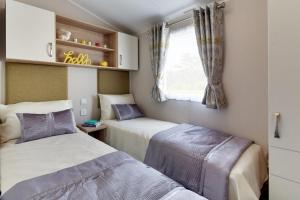 2 camas en una habitación pequeña con ventana en Trossachs Holiday Park, en Drymen