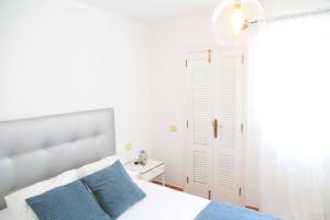 a white bedroom with a bed with blue pillows at La Molina in Cotillo