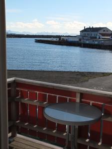 a table on a balcony with a view of the water at Tyskhella Rorbuer in Kabelvåg