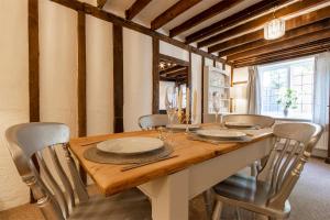 uma sala de jantar com uma mesa de madeira e cadeiras em Primrose Cottage at The Shippe em Bridge