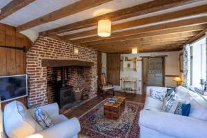 a living room with white furniture and a brick fireplace at Primrose Cottage at The Shippe in Bridge