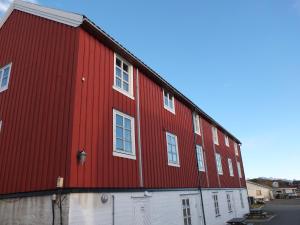 a red barn with white windows and a white garage at Tyskhella Rorbuer in Kabelvåg