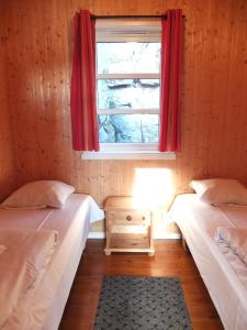 two twin beds in a room with a window at Tyskhella Rorbuer in Kabelvåg