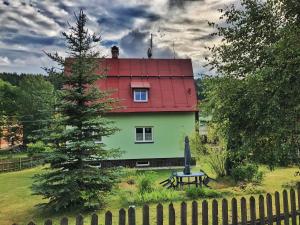 een huis met een rood dak en een bank ervoor bij Horský dům Pernink in Pernink