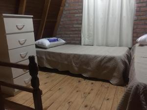 Un dormitorio con una cama y una cómoda y una ventana. en Cabañas Pinar del Este, en Balneario Pehuén-Có