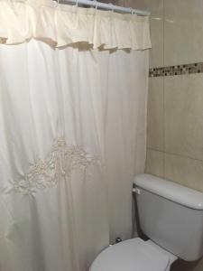 Un baño con una cortina de ducha blanca y un inodoro. en Cabañas Pinar del Este, en Balneario Pehuén-Có
