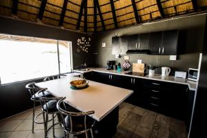 una cocina con armarios negros, mesa y sillas en John-Lou's Studio Flat, en Windhoek