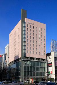 un edificio alto con coches estacionados frente a él en Richmond Hotel Premier Sendai Ekimae en Sendai