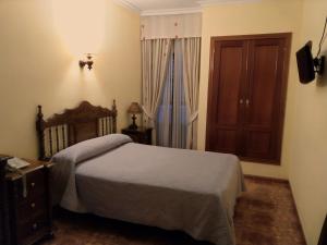 a bedroom with a bed and a dresser and a window at Hostal Bellido in Montilla