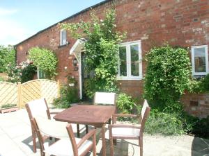 a wooden table and chairs in front of a brick building at Hamlet Cottage sleeps 3-4 Stratford upon Avon in Stratford-upon-Avon