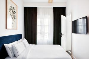 sypialnia z białym łóżkiem i telewizorem w obiekcie Hotel Rendez-Vous Batignolles w Paryżu