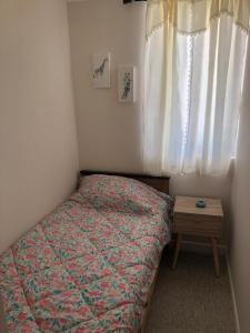 ein kleines Schlafzimmer mit einem Bett und einem Holztisch in der Unterkunft Departamento Nuevo in El Tabo