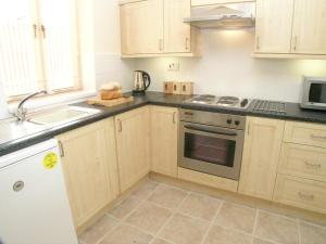 a kitchen with wooden cabinets and a stove top oven at Falstaff Cottage for up to 5, Stratford upon Avon in Stratford-upon-Avon