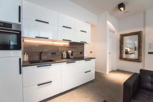 a kitchen with white cabinets and a sink and a couch at Sack-Time fashion boutique hotel in Zandvoort